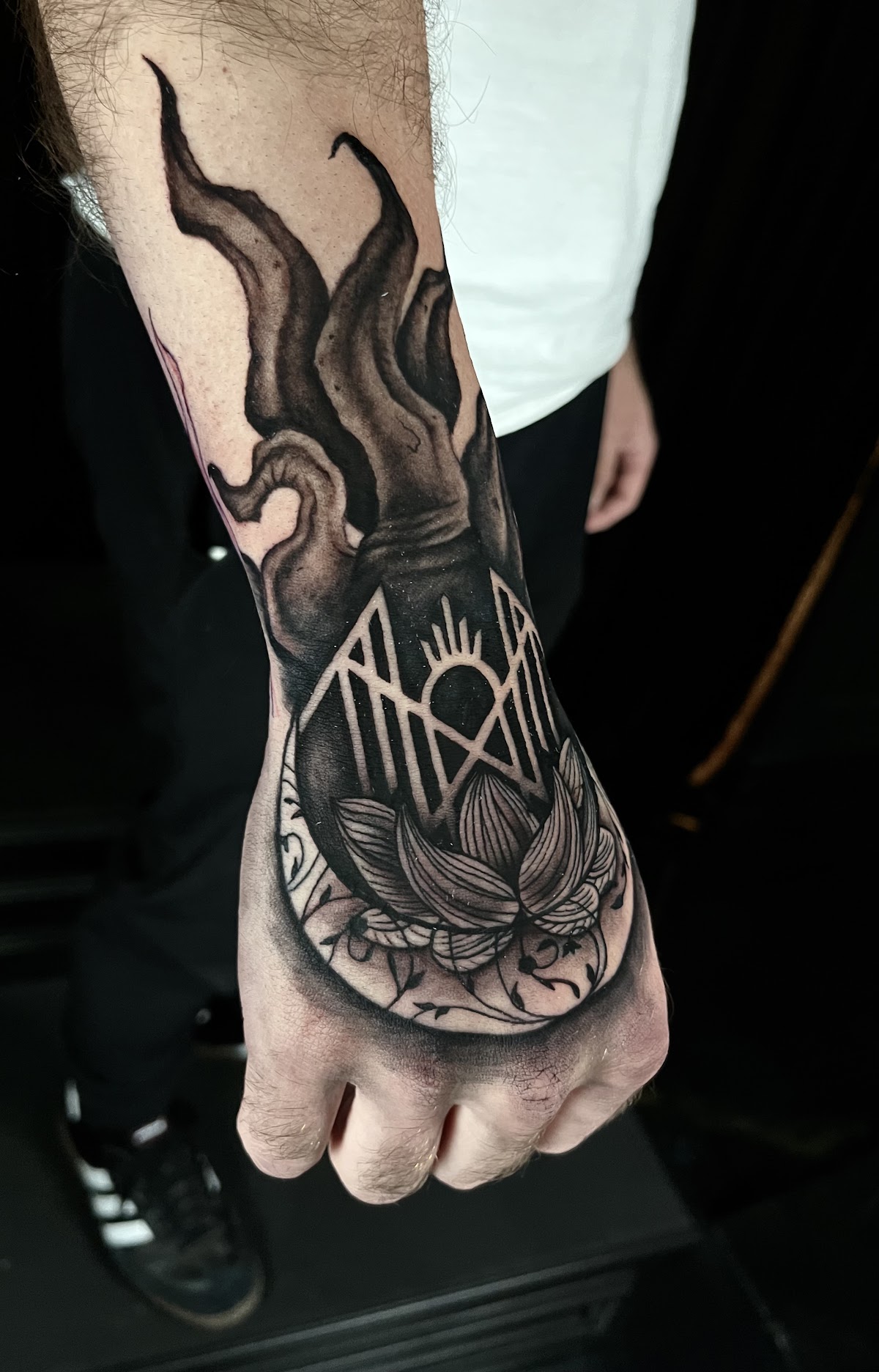 Dark occult hand tattoo with flaming claw and lotus